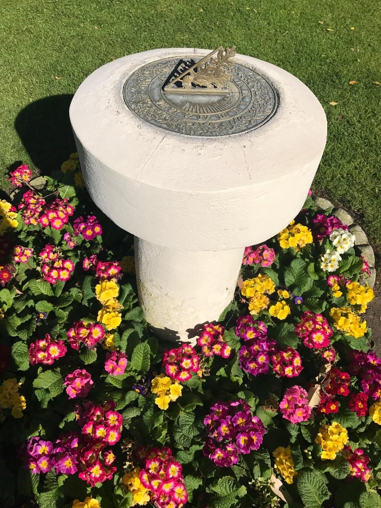 A sundial surrounded by colorful flowers creates a grounded, healing environment for OHI’s spiritual retreat.