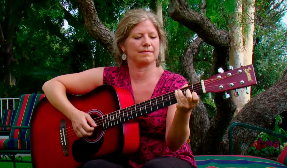 A woman playing soothing guitar melodies during one of OHI’s holistic healing retreats.